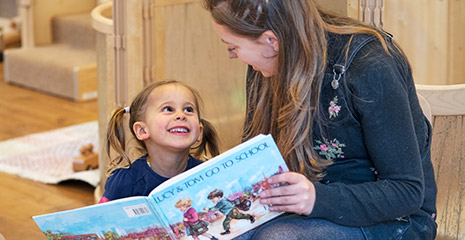A teacher reading to a little girl.