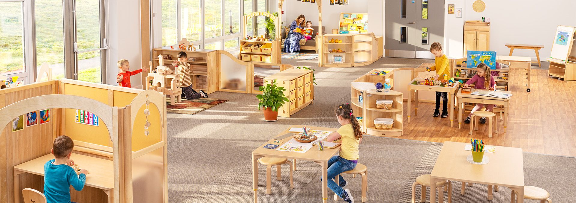 Kinder spielen und lernen in einem hellen, offenen Klassenzimmer mit Roomscapes Möbeln und Raumteilern.