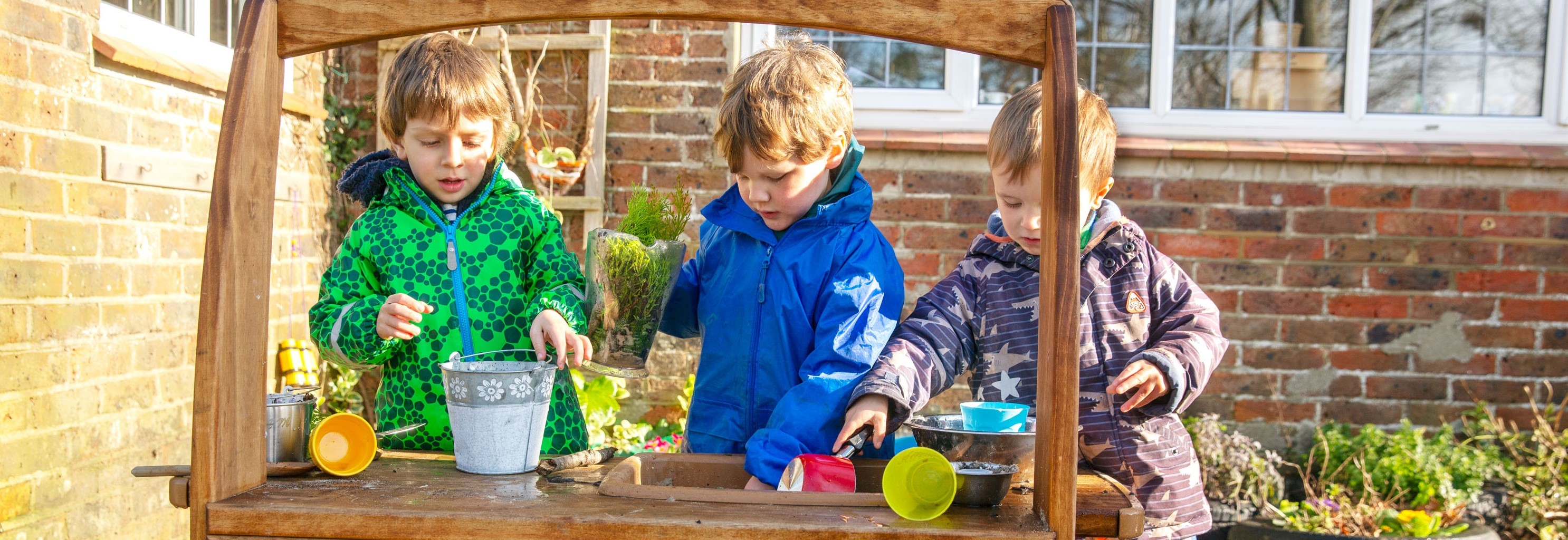 3 Kinder spielen in einer Matschküche