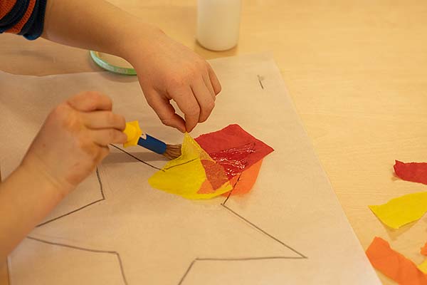 Kinderhände halten Taschentuch und Klebepinsel