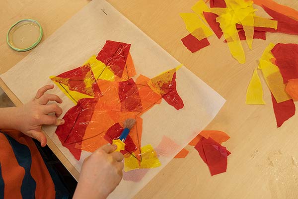Kinderhände über dem Stern, der vollständig mit farbigem Papiertuch bedeckt ist
