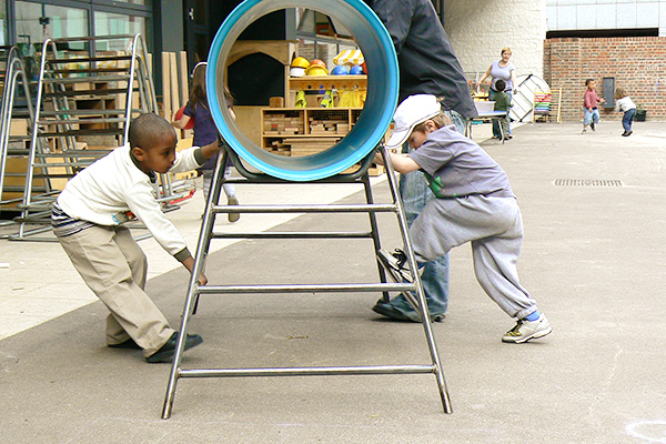 Zwei Kinder kooperieren beim Verschieben eines Spielgeräts