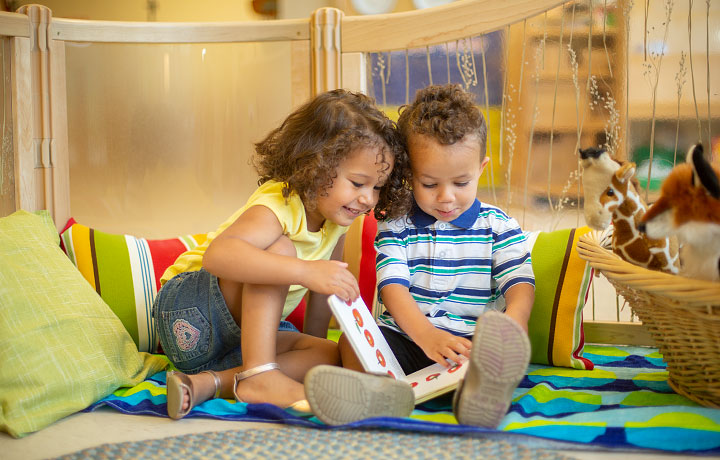Zwei kleine Kinder schauen sich in einer Leseecke ein Buch an