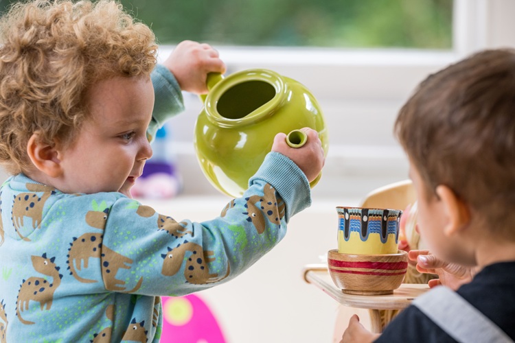 Kind spielt mit einer Teekanne