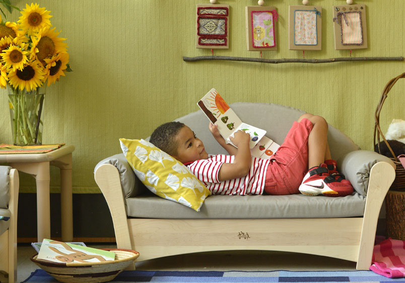 Kind liest auf einem Sofa