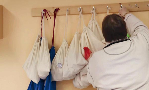 Eine Erzieherin hängt Beutelchen mit heuristischem Material an einer Hakenleiste auf