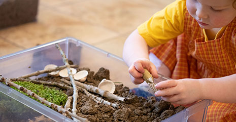 Ein Mädchen spielt mit einer Erdkiste