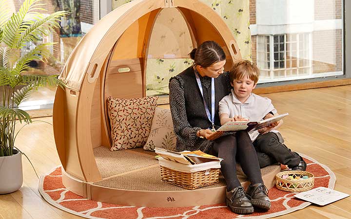 Ein Grundschüler, der gemeinsam mit seiner Lehrerin einen Rückzugsbereich nutzt.