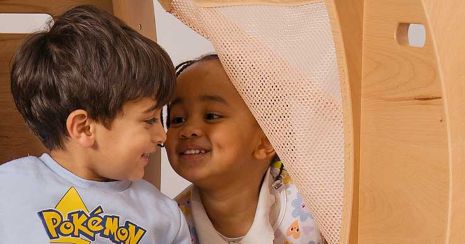 Zwei Kinder lachen zusammen in einem Rückzugsbereich, der aus Massivholz gefertigt wurde.