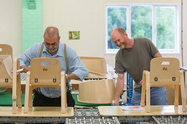 Zwei Mitarbeiter von Community Playthings bei der Produktion von Kinderstühlen