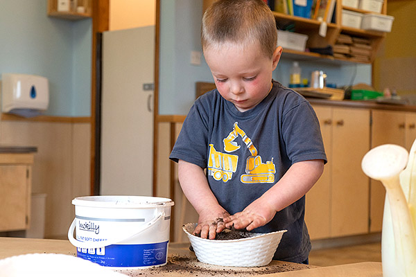 Junge drückt Erde in einem weißen Korb an