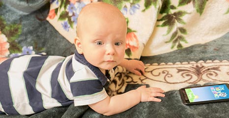 Ein Baby liegt vor einem Smartphone