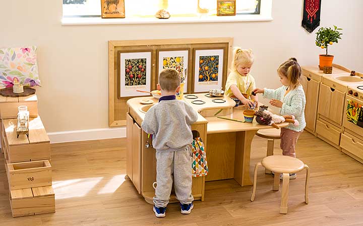 3 Kinder spielen in der Spielküche