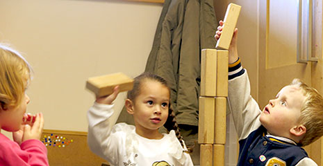 Drei Kinder bauen einen Turm aus Bausteinen