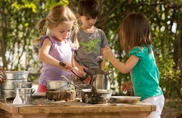 Kinder spielen mit Matsch und natürlichen Materialien an einem Outlast Tisch