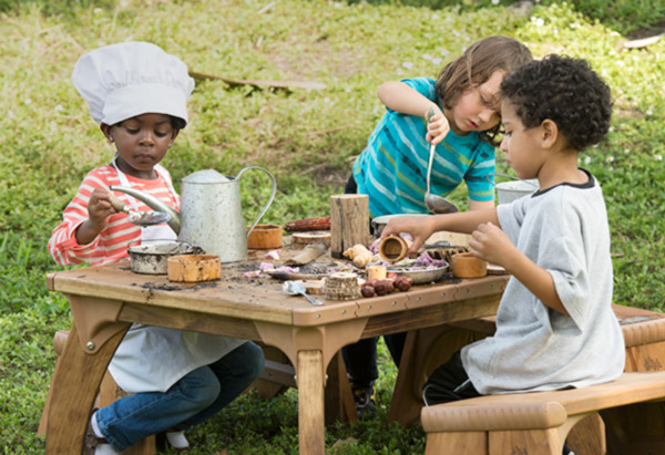 Drei Kinder beim Matschen an einem Outlast Tisch