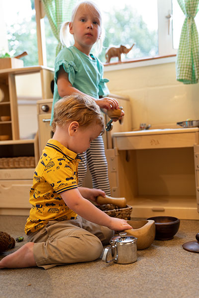zwei Kinder spielen zusammen mit offen gestaltetem Haushaltsmaterial