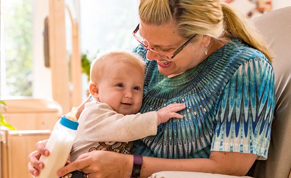 Eine Erzieherin füttert ein Baby
