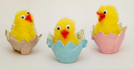 Drei Pomponküken in Nestern aus Eierkarton