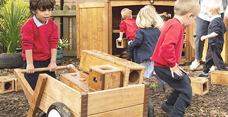 Boy with wheelbarrow transporting wooden blocks