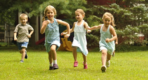 Drei kleine Mädchen laufen über einen Rasen
