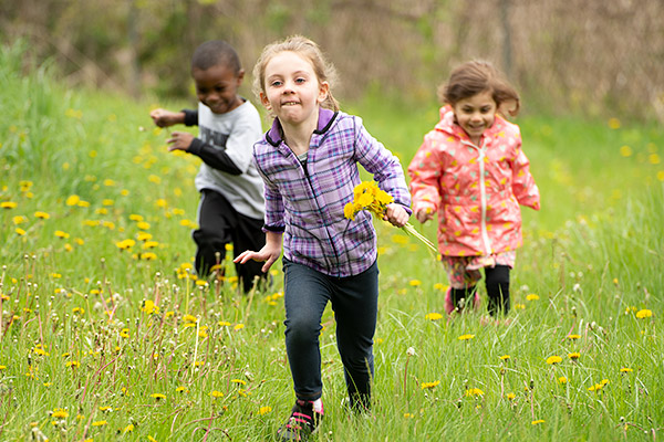 3 Kinder laufen über eine Wiese