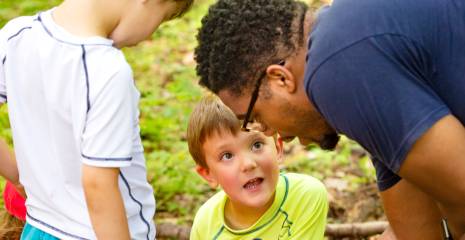 Zwei Kinder und ein Erzieher sprechen miteinander