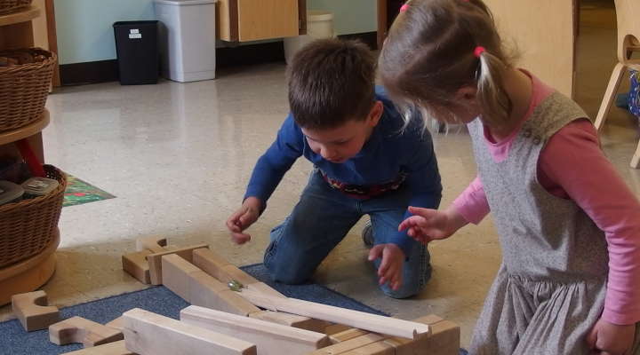 Ein Junge und ein Mädchen spielen mit Bausteinen, Kugelbahnen und Murmeln 