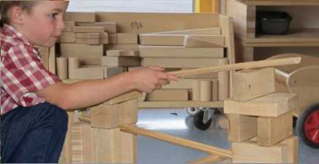 a boy is experimenting with wooden unit blocks and ramps