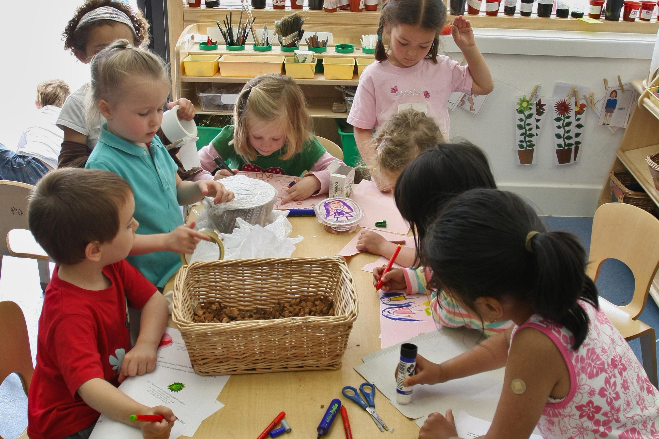 Kinder malen, schreiben und basteln an einem Tisch