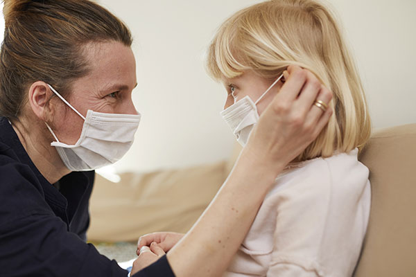 Erzieherin und Kind mit Schutzmasken