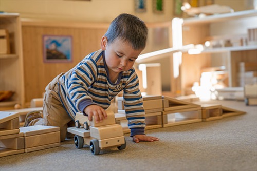 Ein kleiner Junge spielt mit Bausteinen und einem Spielzeugauto