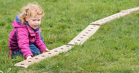 Ein Kindergartenkind legt eine lange Reihe aus Brettern