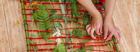 Kinderhände, die mit natürlichen Materialien weben