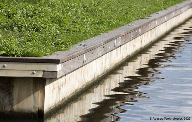 CanalLining: Hölzerne Kanalverkleidung mit grünem Gras oben und Wasser, das die Struktur unten reflektiert.