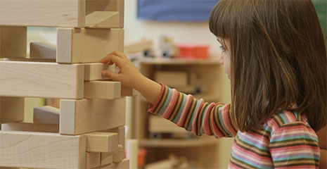 Ein Mädchen baut einen Turm aus Einheitsbausteinen