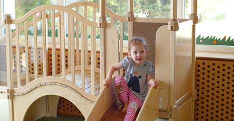 Ein Mädchen rutscht die Rutsche des Bewegungscenters hinunter