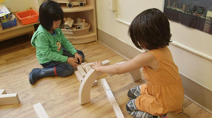 Zwei Kinder bauen einen Bogen mit Einheitsbausteinen