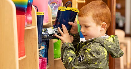 A child packs away his wellies.