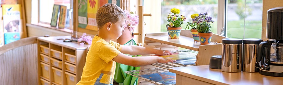 A boy in a yellow shirt placing a picture on a drying rack.