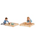 Zwei Babys spielen mit losen Teilen und Naturmaterialien in einem Boden-Sinnestisch ohne Tischplatte.