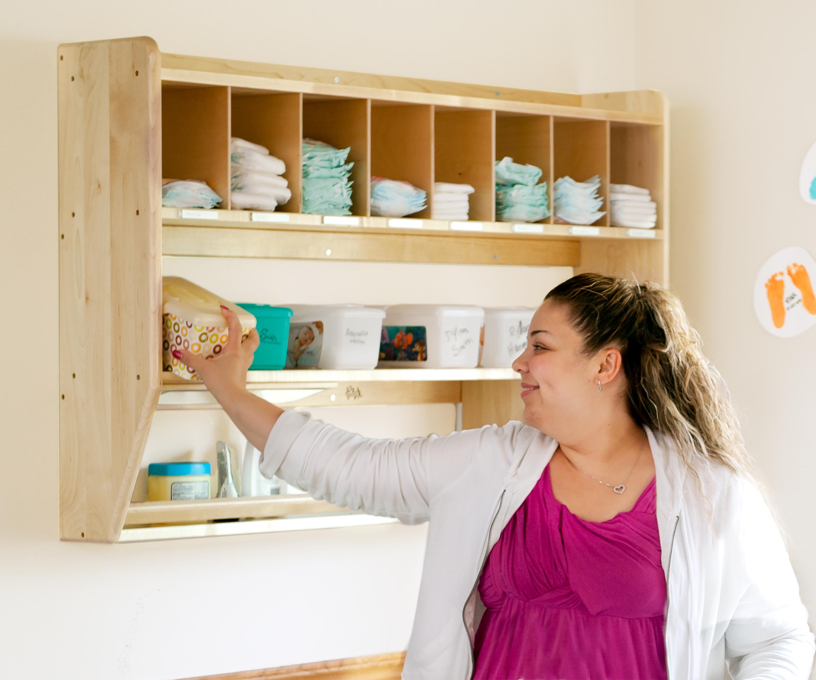 Eine Erzieherin nimmt einen Plastikbehälter aus einem G28 Hängeregal