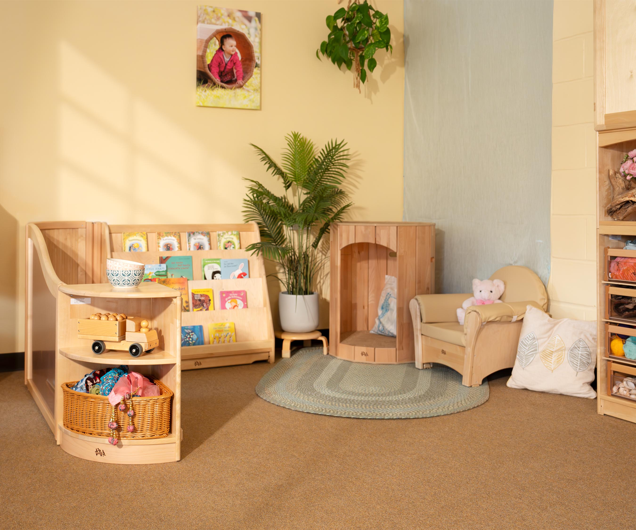 Ein Rückzugsbereich, ausgestattet mit natürlichen Holzmöbeln, einer Baumhöhle, einem Bücherregal und farbenfrohen Materialien.