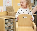 Nursery aged girl carrying solid wood toddler chair