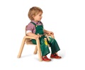 Toddler boy wearing green overalls sitting in a mealtime chair