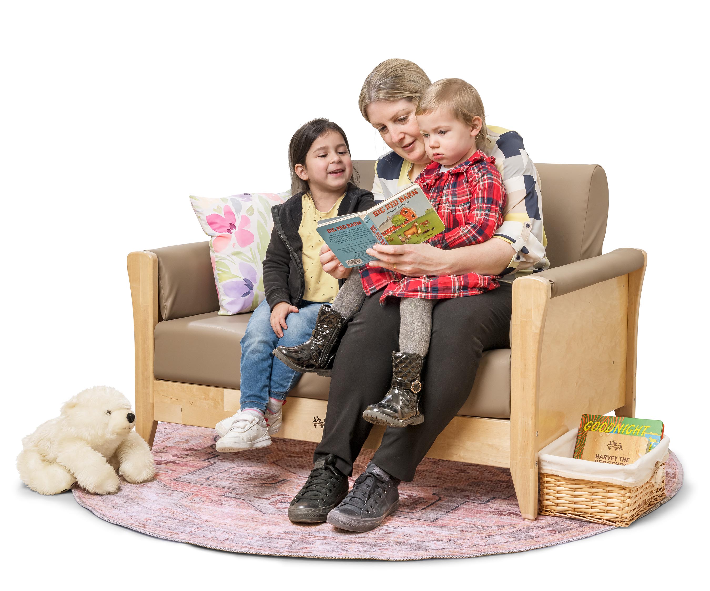 A teacher with two toddlers reading a story on a nursery sofa