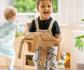 boy dressed in black shirt and overalls and carrying solid wood seat