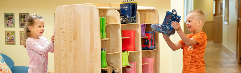 Kinder verstauen Gummistiefel auf einem Stiefelwagen