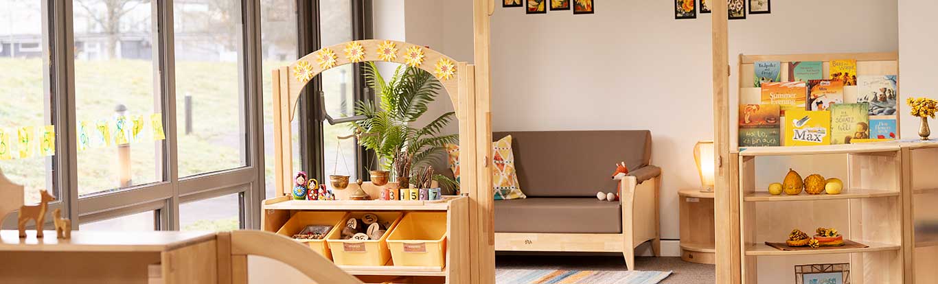 Ein Kitaraum mit großen Fenstern und Massivholzmöbeln
