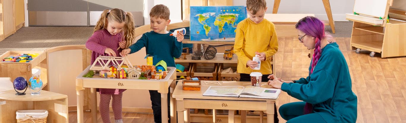 Ein Junge klebt an einem Aktivitätstisch, während andere Kinder an ähnlichen Tischen spielen.